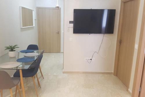 a dining room with a table and a television on a wall at A 200m de la Plage, du Haut Standing au coeur du Parc in Mohammedia