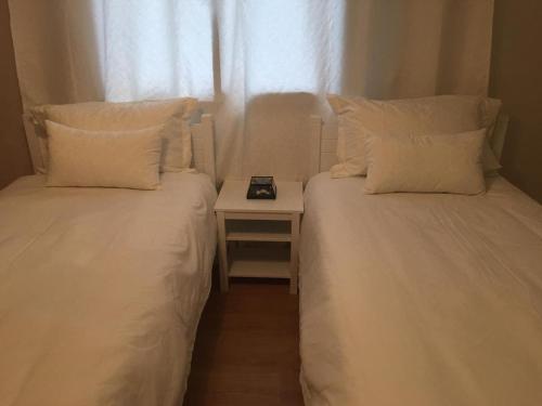 two beds with white pillows and a table with a window at A 200m de la Plage, du Haut Standing au coeur du Parc in Mohammedia