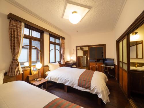 a hotel room with two beds and a television at Inase Otsu Machiya Bed and Breakfast in Otsu