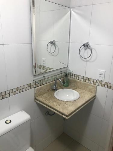 uma casa de banho com um lavatório, um espelho e um WC. em Apartamento Praia do Forte - Cabo Frio em Cabo Frio