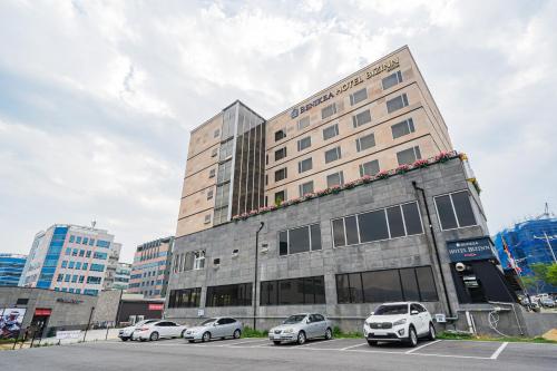 a building with cars parked in a parking lot at Benikea Hotel Bizinn in Wonju