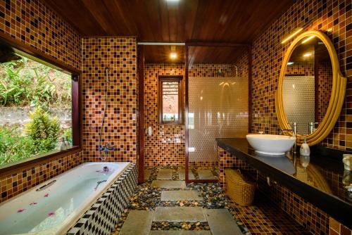une salle de bain avec une baignoire, un lavabo et un miroir dans l'établissement Sankofa Village Hill Resort & Spa, à Hue