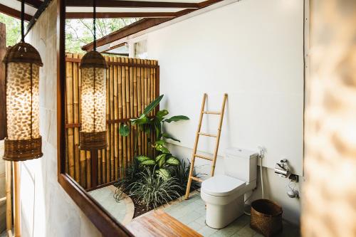a bathroom with a toilet and plants on a balcony at The Seraya Resort Komodo in Labuan Bajo