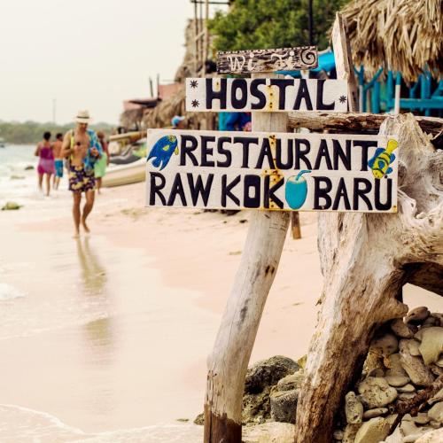 a sign on a beach with people walking on the beach at Raw KokoMar PosadaNativa in Baru