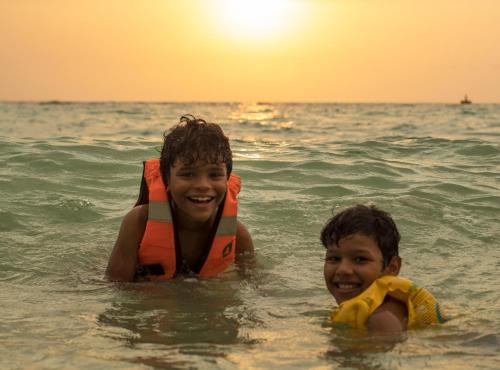 two young boys in the ocean with a life jacket at Raw KokoMar PosadaNativa in Baru