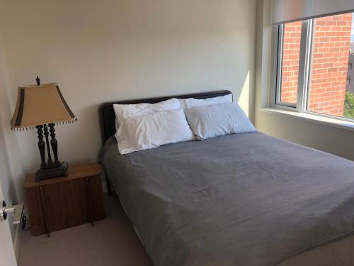 1 dormitorio con 1 cama con lámpara y ventana en Downtown 2 beds/2bath with huge patio& parking! en Victoria