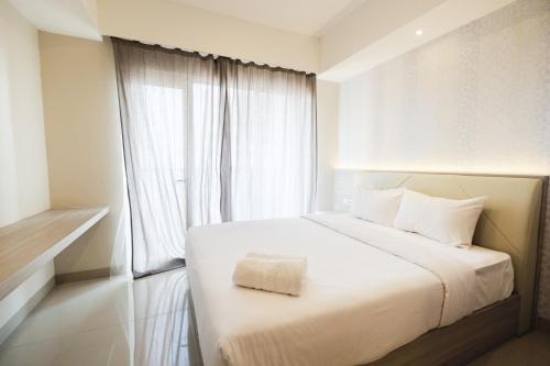 a bedroom with a white bed and a window at Cozy 1BR Oasis Apartment By Travelio in Bekasi
