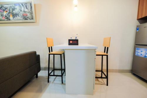 a kitchen with a counter and two stools at Cozy 1BR Oasis Apartment By Travelio in Bekasi