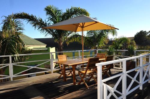 a wooden table and chairs with an umbrella on a deck at Alte Villa G&auml;stehaus in L&uuml;deritz