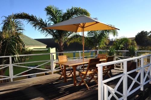 uma mesa e cadeiras de madeira com um guarda-sol num deque em Alte Villa Gästehaus em Lüderitz