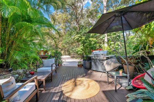 a patio with a table and chairs and an umbrella at Noosa Hinterland Retreat in Tinbeerwah
