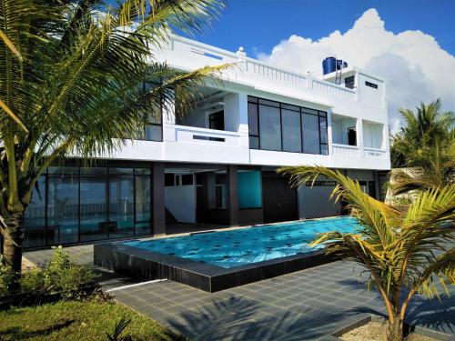 une maison blanche avec une piscine en face de celle-ci dans l'établissement Mandabelle villa tanjung lesung banten, à Tanjung Lesung