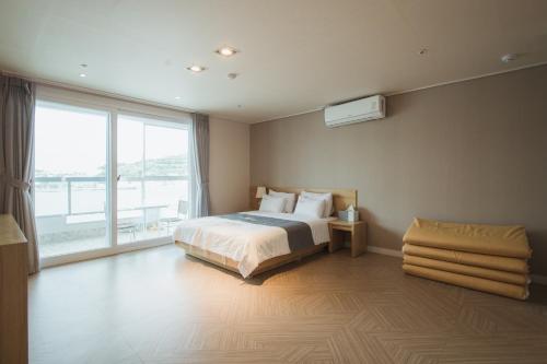 a bedroom with a bed and a large window at Lium Spa Hostel in Yeosu