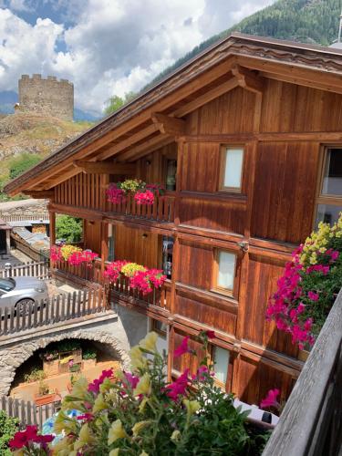 a wooden building with flowers on the balcony at Hotel Il Maniero in Ossana