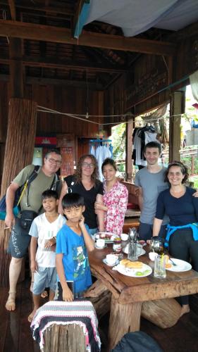 a group of people sitting around a wooden table at Ratanak Tep Rithea homestay in Banlung