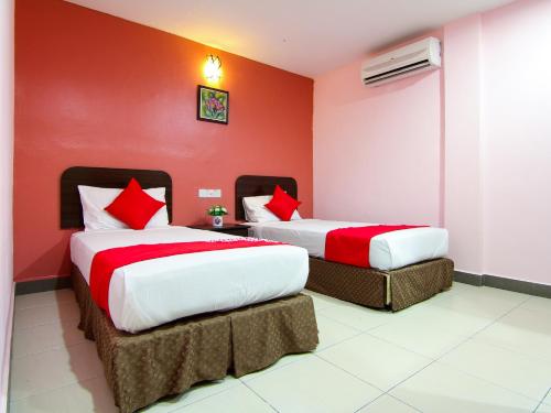 twee bedden in een kamer met rode muren bij OYO 11343 Hotel Putra Iskandar in Seri Iskandar