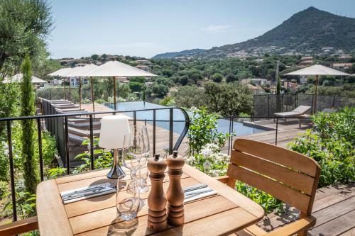 a wooden table with wine glasses on a balcony at Hôtel Restaurant Villa Joséphine in LʼÎle-Rousse
