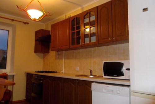 uma cozinha com armários de madeira e um micro-ondas em Comfortable apartments in centre with 3 bedrooms em Rivne