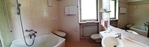 a bathroom with a sink and a tub and a toilet at Hotel Rodes in Ortisei
