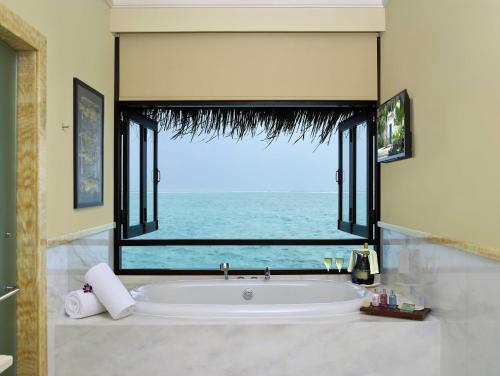 a bathroom with a large mirror and a tub at Taj Exotica Resort & Spa in South Male Atoll