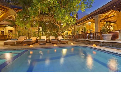 a swimming pool with lounge chairs and a house at Bali Agung Village - CHSE Certified in Seminyak