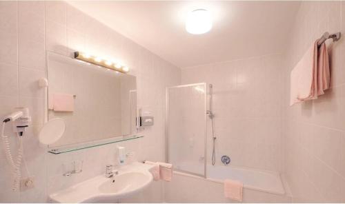 a white bathroom with a sink and a shower at Sporthotel Kühtai in Kühtai