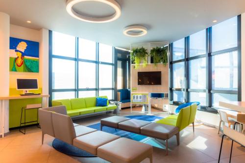 a living room with yellow and green furniture and windows at Airport Hotel Bergamo in Bagnatica