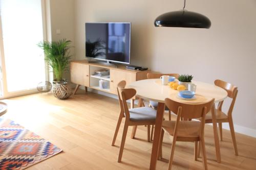 uma sala de estar com uma mesa com cadeiras e uma televisão em Lake View Apartment em Iława