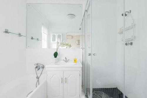 Banana palm luxury cottage في ديربان: حمام أبيض مع حوض ودش