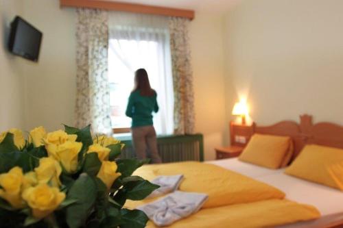 a woman standing in a bedroom with a bed with yellow flowers at Gasthof Gnasmüller in Totzenbach