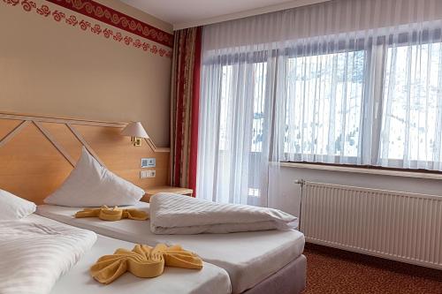 a hotel room with two beds with yellow shoes on them at Sporthotel Kühtai in Kühtai