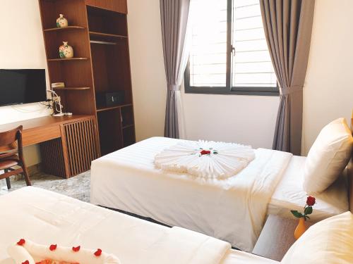 a hotel room with two beds and a desk at Hanoi La Cascada House & Travel in Hanoi