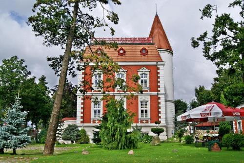 a large red and white house with a tree in the yard at VILLA RED by COLUMBUS Ustka in Ustka