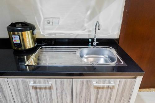 a kitchen counter with a sink and a coffee pot at Premium 1BR Apartement At Grand Sungkono Lagoon By Travelio in Surabaya