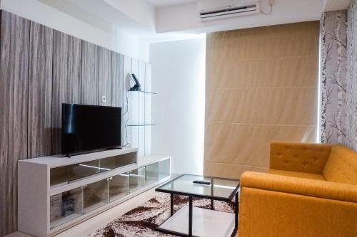 a living room with a television and a chair at Premium 1BR Apartement At Grand Sungkono Lagoon By Travelio in Surabaya