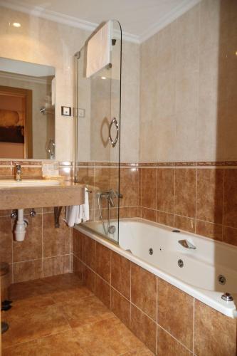 a bathroom with a bath tub and a sink at Hotel Restaurante Casa Pipo in Tuña