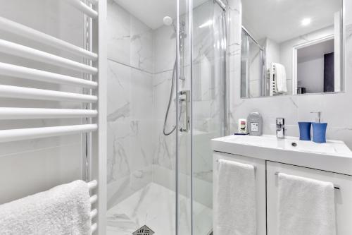 une salle de bain blanche avec une douche et un lavabo dans l'établissement 93 - Luxury Flat in Le Marais, à Paris