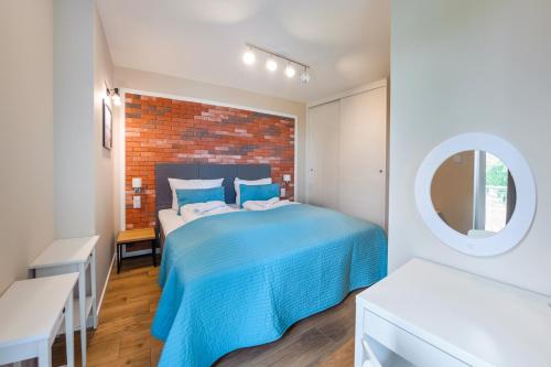 a bedroom with a blue bed and a brick wall at Klifowa Rewal, Sun & Snow in Rewal