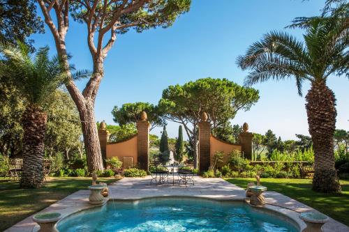 a backyard with a pool and palm trees at L'Andana Tenuta La Badiola in Castiglione della Pescaia