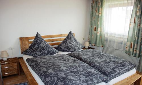 a bedroom with a bed with blue and gray sheets and a window at Ferienwohnung Dichtl in Grafenau