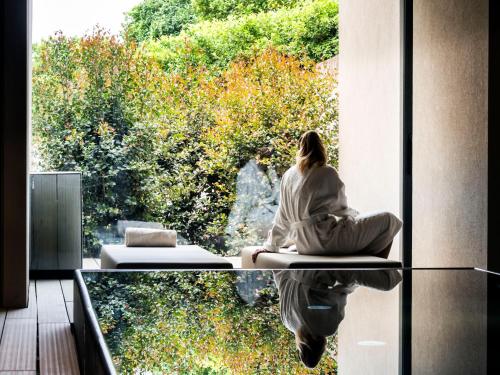 a woman sitting on a window sill looking out at trees at Zash Country Boutique hotel & SPA in Giarre