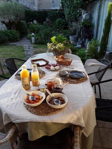 uma mesa com pratos de comida e garrafas de sumo de laranja em La Petite Maison em Laroque-Timbaut