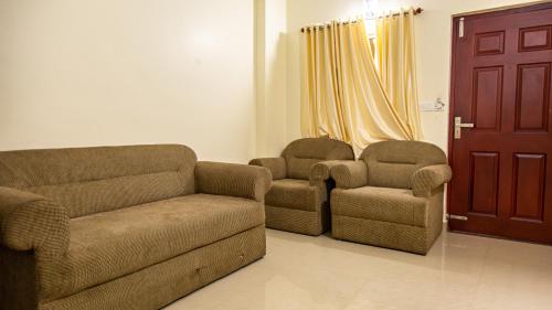 a living room with a couch and two chairs at Woodside residency in Thekkady