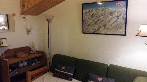 a living room with a couch and a picture on the wall at Appartement dernier étage au pied des pistes HIRMENTAZ in Bellevaux