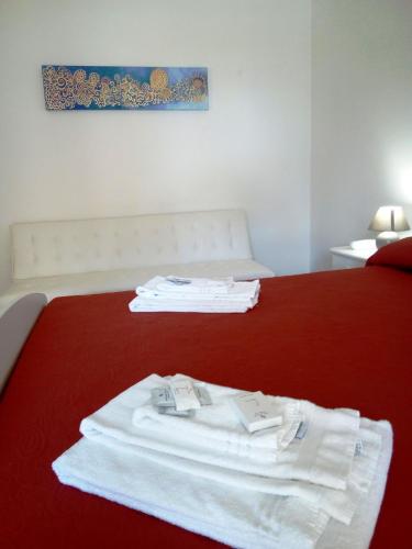 a bedroom with a red bed with white towels on it at Al Saliceto Hotel in Patti