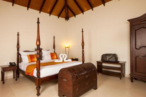 a bedroom with a large bed with a wooden canopy at Old Kent Estates & Spa, Coorg in Suntikoppa