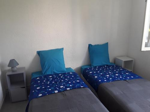 2 camas en una habitación con almohadas azules en La villa en Le Vigan