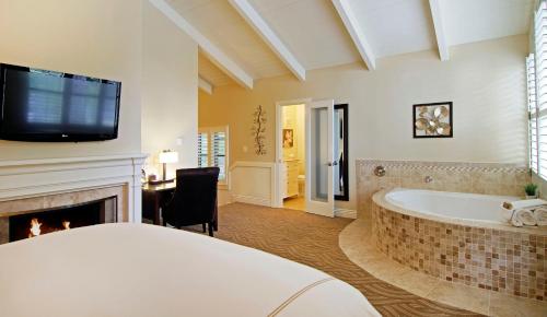 a bathroom with a tub and a tv over a fireplace at Carriage House Inn in Carmel