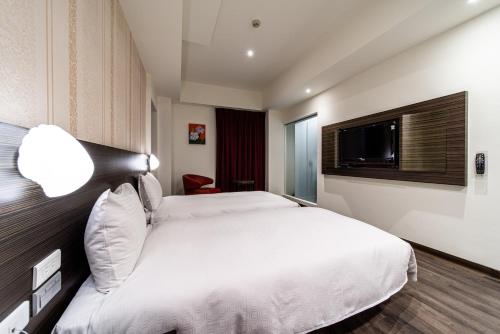 a hotel room with a bed and a television at Fish Hotel - Yancheng in Kaohsiung