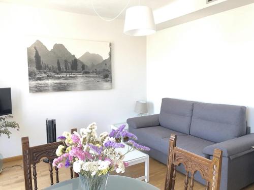 a living room with a couch and a table with flowers at La Casa de Mansilla in Mansilla de las Mulas